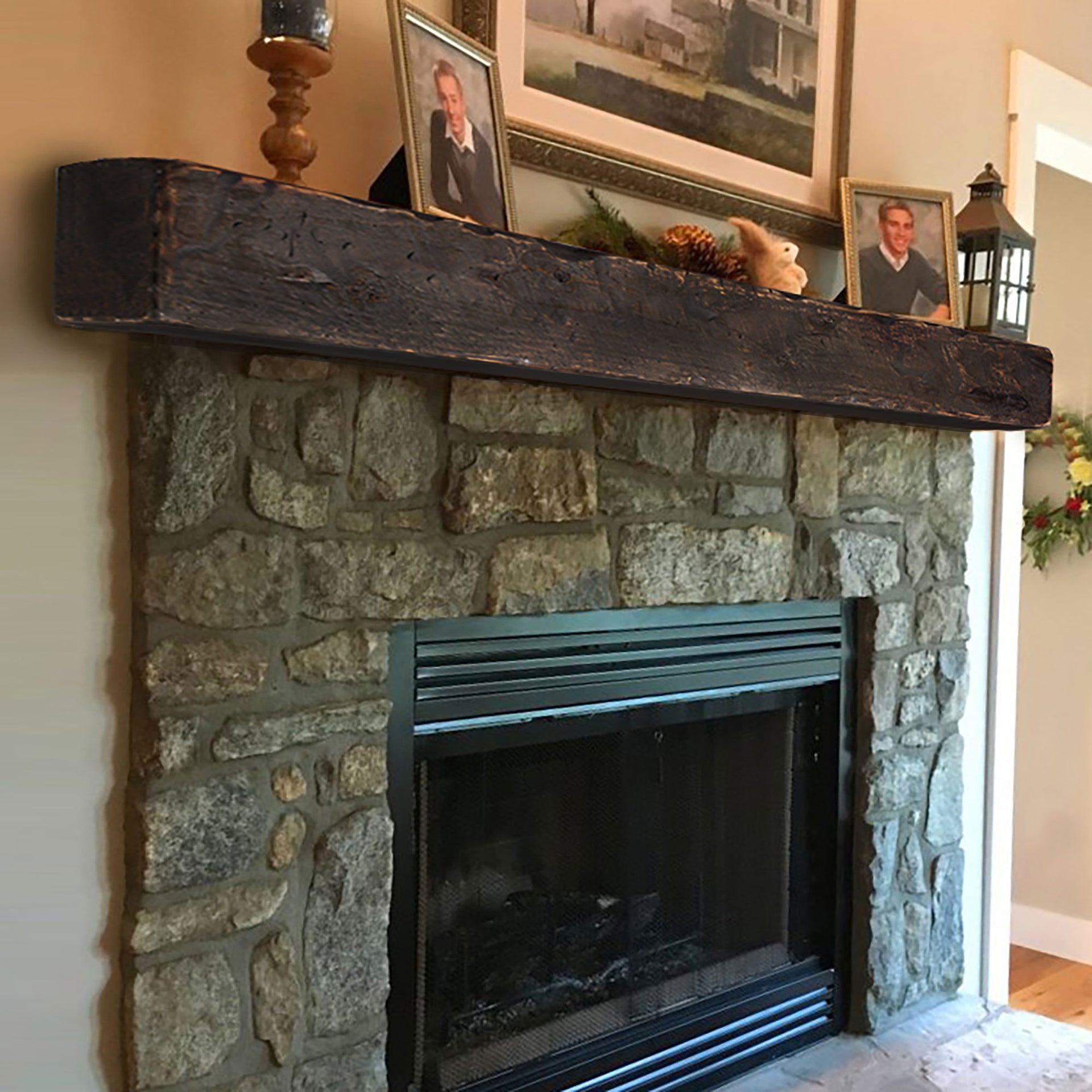A walnut rustic mantel sitting on a rustic stone fireplace