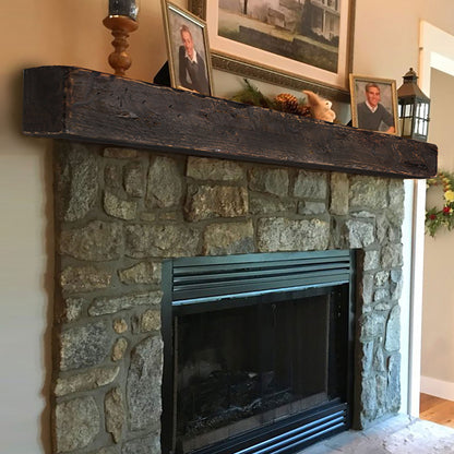 A walnut rustic mantel sitting on a rustic stone fireplace