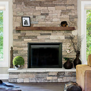 A floating mantel installed on a floor to ceiling limestone and granite fireplace
